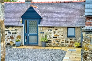 A stone building with a dark blue door, a small window, and potted plants. - 1 Bed in Pwllheli (oc-tywoms) (Abersoch)