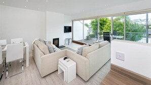 A modern living room with a sofa set, a TV, and a dining area. - 2 Bed in Pwllheli (oc-45caed) (Abersoch)