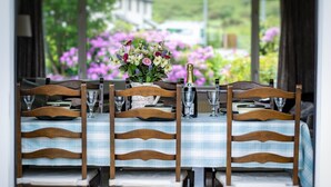 Una mesa de comedor dispuesta con sillas de madera, un centro de mesa floral y una botella de champán.