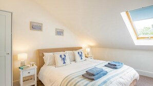 Een slaapkamer met een bed, twee nachtkastjes, een raam en uitzicht op het landschap.