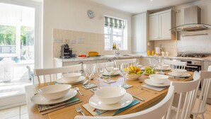 Een moderne keuken met witte kastjes, een eettafel voor vier personen en uitzicht op de omgeving.