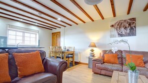 A living room with leather sofas, wooden beams on the ceiling, a dining table with chairs, and a window with blinds. - 2 Bed in Y Felinheli (oc-wag430) (Y Felinheli)
