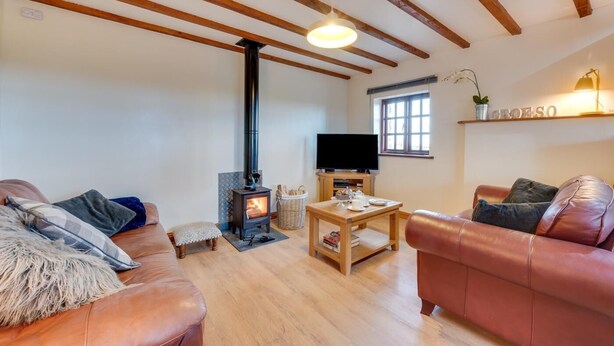 A cozy living room with a fireplace, leather sofas, a television, and wooden beams on the ceiling. - 2 Bed in Y Felinheli (oc-wag430) (Y Felinheli)