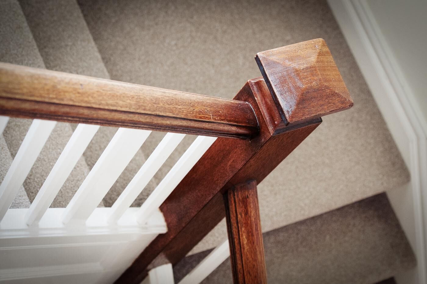 Une main courante en bois avec une balustrade blanche.