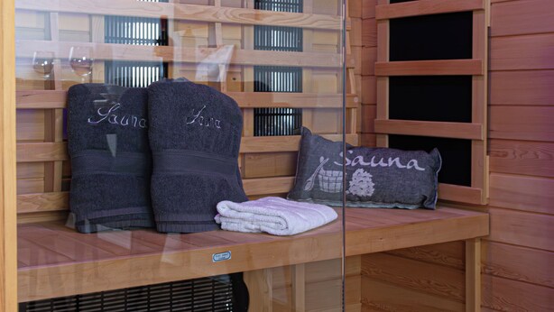Una sauna con paredes y bancos de madera, toallas y un panel de vidrio.
