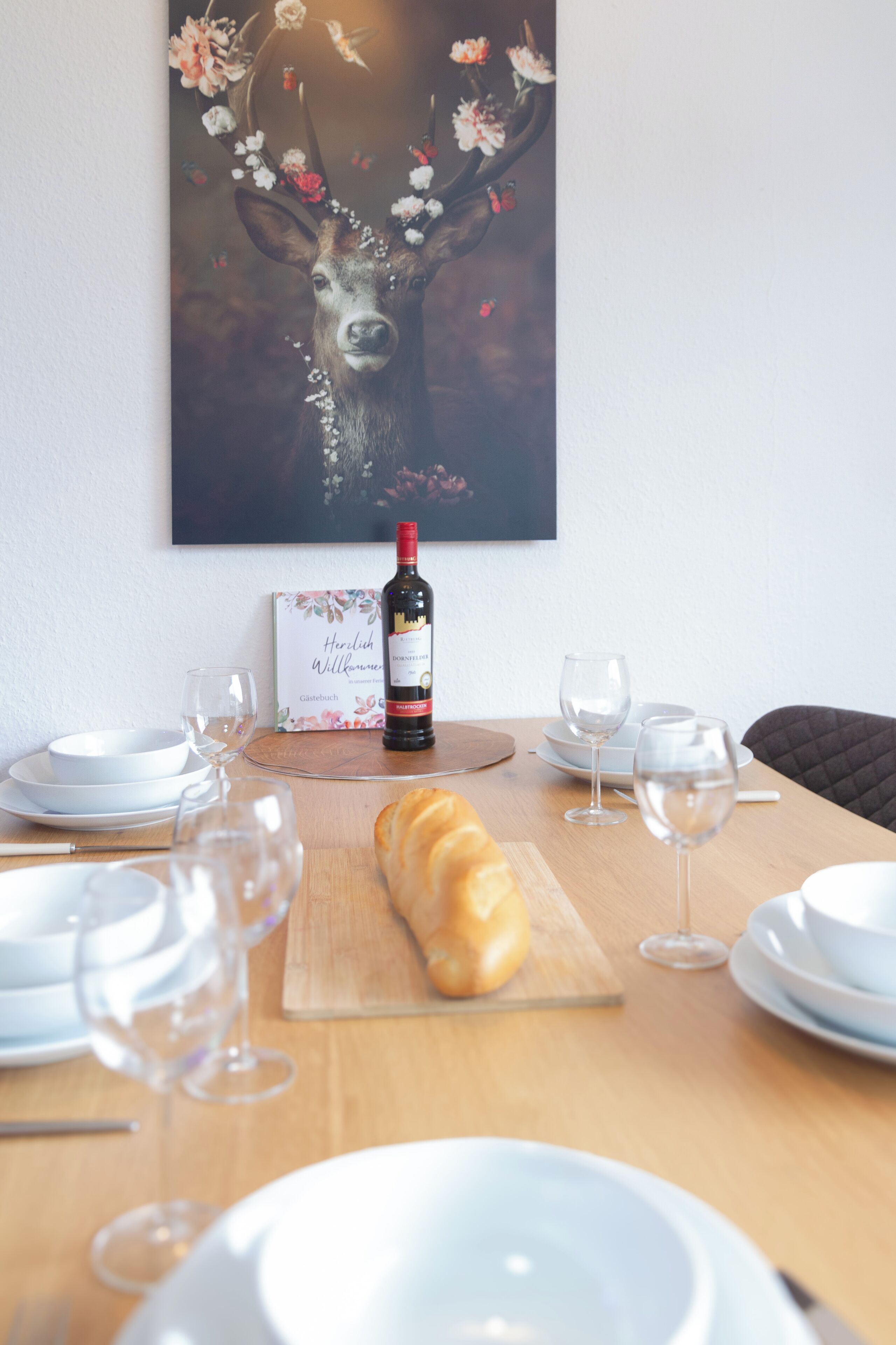 Een eettafel met een brood, een fles wijn en lege wijnkannen.