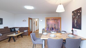 Una sala moderna con un sofá, una mesa de centro y un comedor con mesa dispuesta para cuatro.