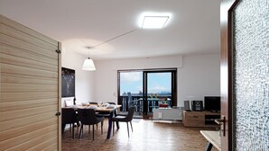 Una cocina moderna con armarios de madera, un comedor con mesa y sillas, y un amplio ventanal con vistas al exterior.