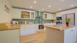 A modern kitchen with white cabinetry, a central island, and a built-in oven. - 4 Bed in Fakenham (oc-1261) (Thursford)