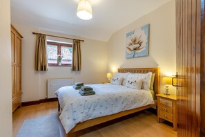 A bedroom with a bed, bedside tables, a radiator, a window with curtains, and a painting on the wall. - 2 Bed in Lyng (oc-864) (Lyng)