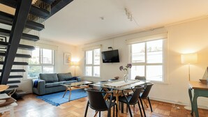 Amplia sala de estar con mesa de comedor, sillas, sofá y escalera.