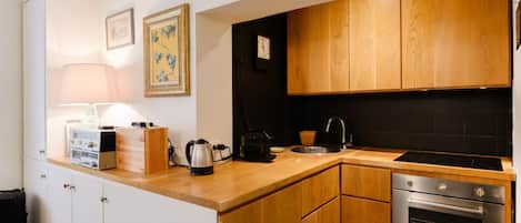 A modern kitchen with wooden cabinets, a built-in oven, and a coffee maker.