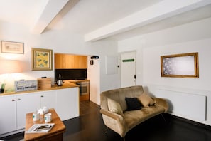 Ein modernes Wohnzimmer mit einer Couch, einem Couchtisch und einer dahinterliegenden Küchenzeile.