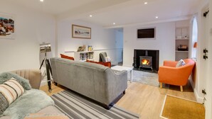 A modern living room with a grey sofa, orange armchair, and a fireplace.