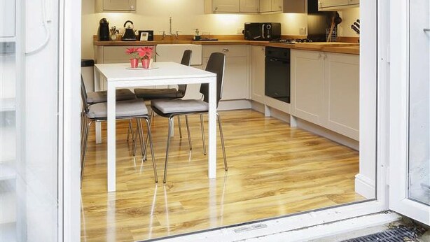 A modern kitchen with white cabinets, a wooden countertop, and a dining area with a white table and chairs.