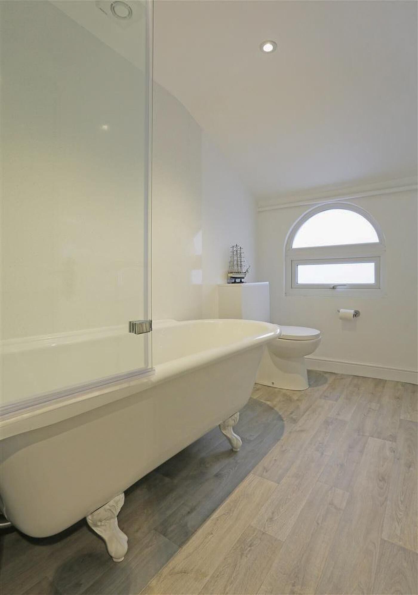 A bathroom with a freestanding bathtub, a toilet, and a window.