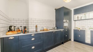 Eine moderne Küche mit dunkelblauen Schränken, weißen Arbeitsplatten und einer gefliesten Spritzschutzwand.