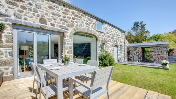 A stone house with a patio table and chairs, a stone building in the background, and a grassy yard. - 3 Bed in Botwnnog (oc-wag571) (Botwnnog)
