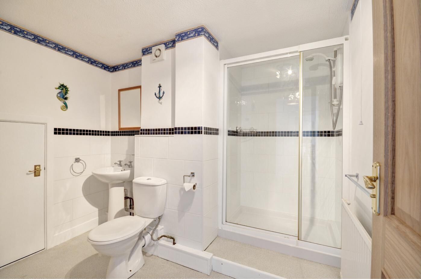 A bathroom with a toilet, sink, and glass-enclosed shower.