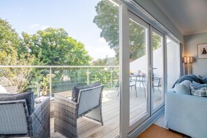 A balcony with wicker furniture, a dining table, and a sofa. - 2 Bed in Llanbedrog (oc-3glyny) (Llanbedrog)