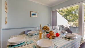 A dining area with a table set for four, including plates, glasses, and a bottle. - 2 Bed in Llanbedrog (oc-3glyny) (Llanbedrog)