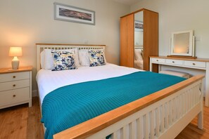 A bedroom with a bed, a nightstand, a dresser, and a mirror. - 2 Bed in Abersoch (oc-taflia) (Abersoch)