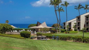 A resort with a pool, outdoor seating, and a view of the ocean.