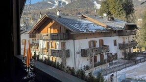 A mountain chalet with a wooden facade, balconies, and a view of snow-capped mountains.