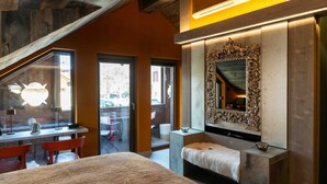 A modern bedroom with a large bed, a vanity with a mirror, and a desk with chairs.