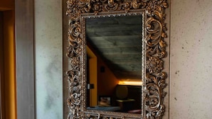 An ornate mirror with a decorative frame mounted on a textured wall.