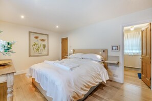 A neatly made bed with white linens, a wooden headboard, a framed botanical print on the wall, and a wooden nightstand with a lamp. - 4 Bed in Helmsley (oc-y039) (Helmsley)