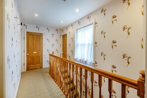 A hallway with floral wallpaper, a wooden door, and a window with sheer curtains. - 4 Bed in Helmsley (oc-y039) (Helmsley)