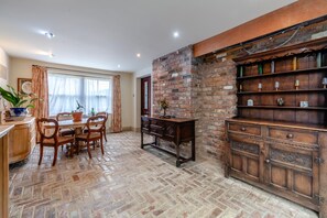 A dining area with a brick wall, wooden furniture, and a brick floor. - 4 Bed in Helmsley (oc-y039) (Helmsley)