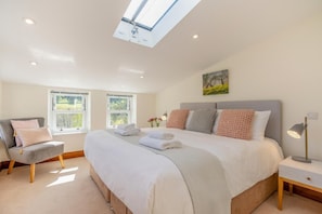 A bedroom with a large bed, a chair, a bedside table, and a skylight. - 3 Bed in Gunnerside (oc-ds097) (Gunnerside)