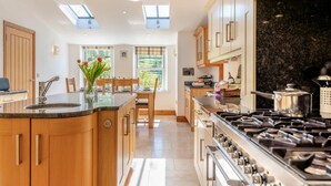 Una cocina moderna con una isla central, armarios de madera, una estufa y tragaluces.