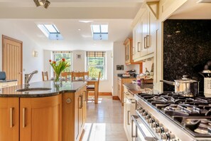 A modern kitchen with a central island, wooden cabinets, a stove, and skylights. - 3 Bed in Gunnerside (oc-ds097) (Gunnerside)