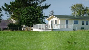 Une maison avec une clôture blanche, une pelouse verdoyante et un arbre en arrière-plan.