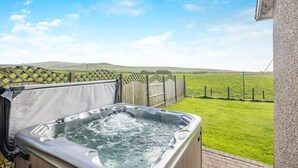 A hot tub on a patio with a view of a grassy field and hills. - 3 Bed in Aberdaron (oc-203206) (Aberdaron)