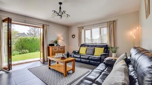 Ein modernes Wohnzimmer mit einer Ledersofa, einem Holztisch und einer Pendelleuchte.