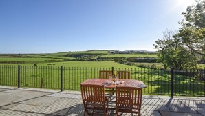 Eine Terrasse mit Tisch und Stühlen mit Blick auf ein grünes Feld.