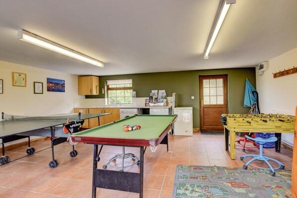 A room with a pool table, foosball table, and a ping pong table.