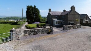 A stone house with a large window and a covered patio area. - 4 Bed in Caernarfon (oc-30479) (Dinas)