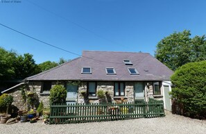 A stone house with a sloped roof, a porch, and a green fence. - 2 Bed in Llandysul (oc-23391) (Ffostrasol)