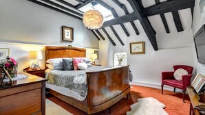 Une chambre à coucher avec un lit en bois, une chaise rouge et une grande fenêtre donnant sur le ciel.