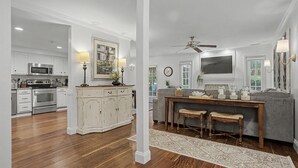 A spacious living room with a gray sofa, wooden coffee table, and a ceiling fan. - Evian 157- 2BR/2BA Pool & Tennis Courts (Hilton Head Island)
