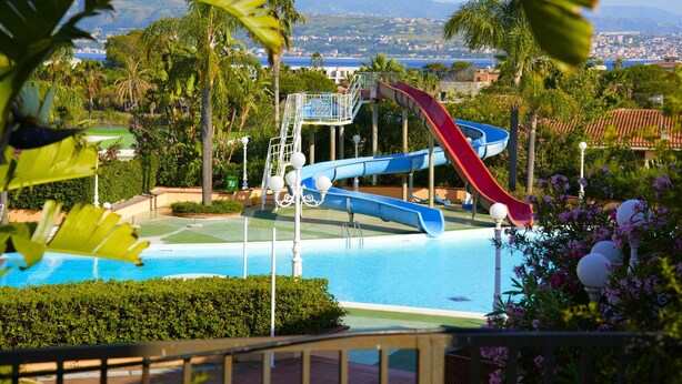 A water park with multiple slides, a pool, and a view of a coastal town. - Discover your exclusive oasis in Ganzirri: the villa overlooking the Strait (Messina)