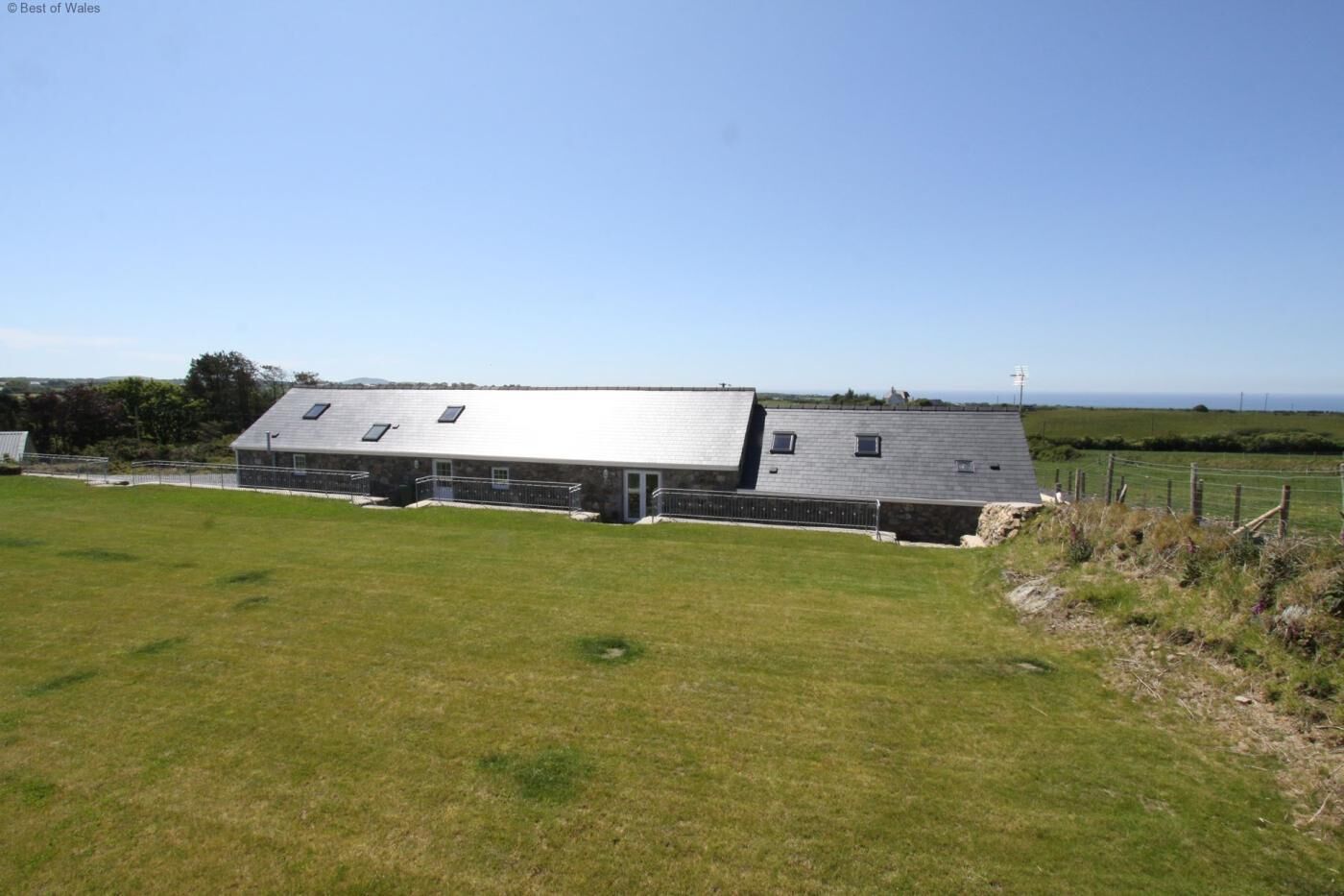 A large, single-story barn with a sloped roof and multiple windows.
