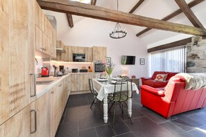 Eine moderne Küche mit Holzausstattung, einem Esstisch mit Stühlen und einem roten Sofa im Wohnbereich.