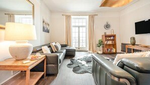 A modern living room with a sofa, a coffee table, a lamp, and a bookshelf. - 2 Bed in Tenby (oc-25953) (Tenby)