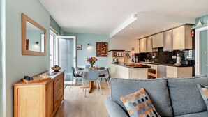 A modern kitchen with wooden cabinets and a dining area with a table and chairs. - St Mary's Seaview - In Town Walls, Close to Beach (Tenby)